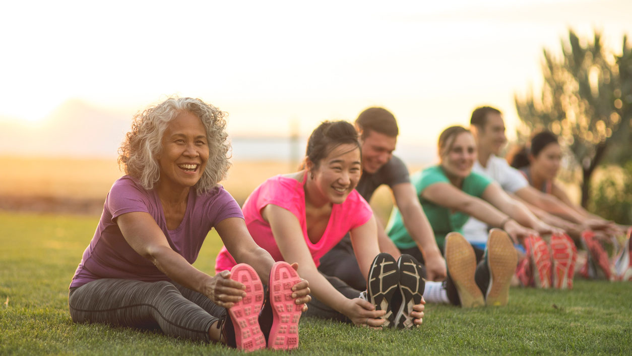 fitness class stretching Adults stretching outside and smiling.